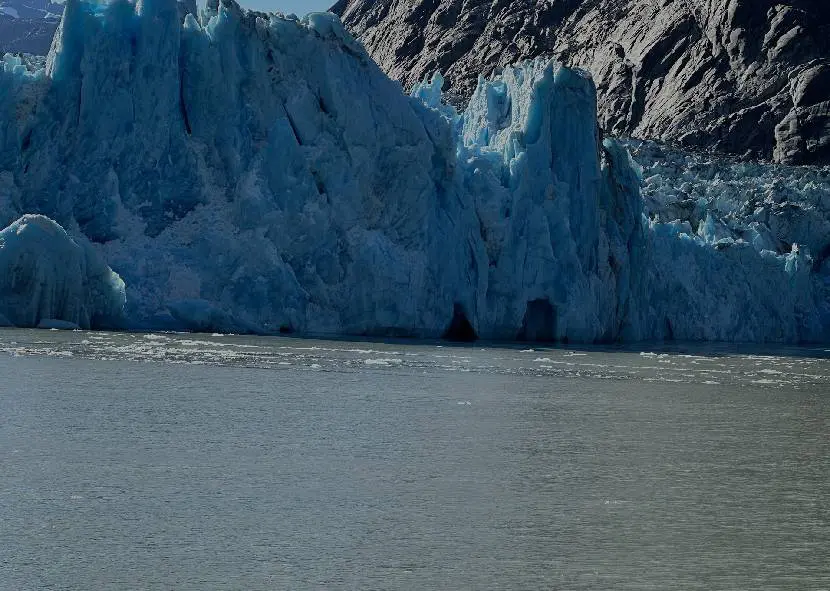 Blue glacial ice rising above the water